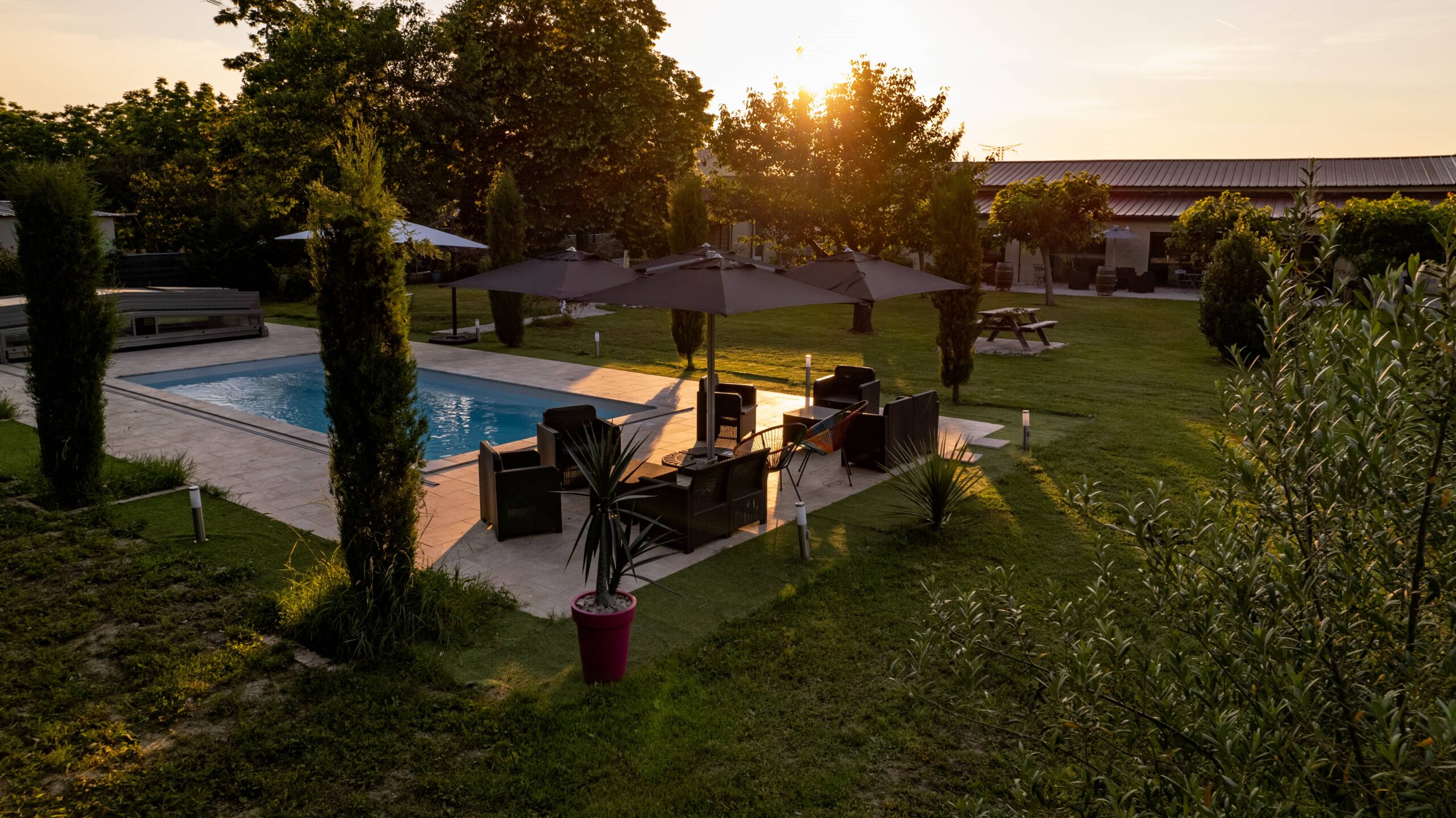 Piscine au coucher du soleil avec salon de jardin au domaine-des-oliviers près de Toulouse